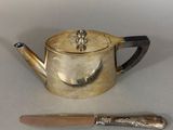 a silver tea pot and a knife on a table