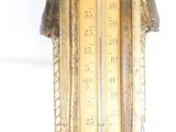 a gold clock with a thermometer on top of it