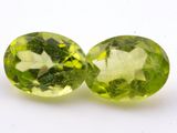 pair of two oval green peridotites on a white surface