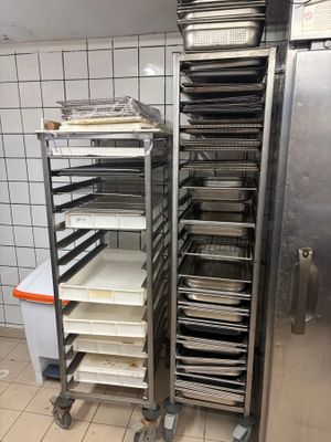 several trays of food are stacked on a metal rack in a kitchen