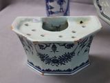 a blue and white vase with a candle holder in it
