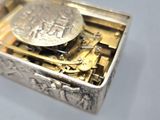 a silver box with a silver coin inside of it
