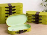 three green boxes with brown handles sitting on top of a wooden table