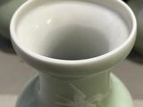 a green vase sitting on a table with other vases in the background