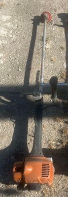 an orange and black blower sitting on the ground next to a pole