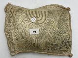 un coussin doré orné d'une menorah, posé sur une surface blanche