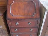 a small wooden cabinet with drawers next to a dresser