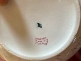 a person holding a white vase with a green bird on it