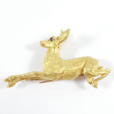 une image représentant une broche en forme de cerf en or aux yeux bleus