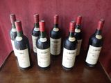 six bottles of red wine are lined up on a table