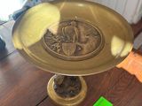 a gold plate on a wooden table with a green tag on it