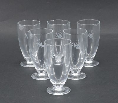 six verres à vin transparents sont alignés sur une surface noire