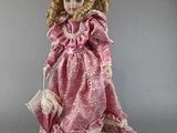 an antique doll with blonde hair wearing a pink dress and holding a purse