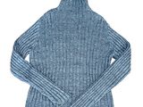 Le pull est bleu et présente un motif côtelé.