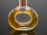 a close up of a bottle of perfume on a reflective surface