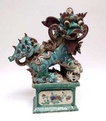 statue of a dragon with a ball in its mouth on a pedestal