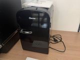 a small coffee maker on a desk next to a computer
