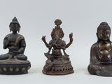 three bronze statues of buddhas sitting on top of a white surface