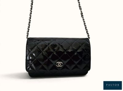 un sac Chanel noir avec une bandoulière en chaîne sur fond blanc