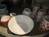 many plates and cups on the corner of a shelf