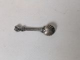 a silver spoon with a shell on it on a white surface