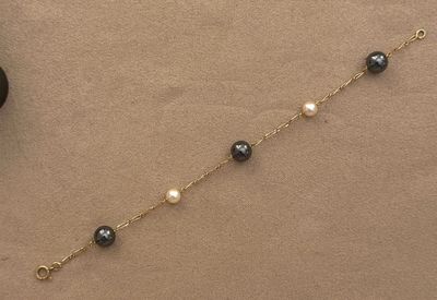a close up of a black and white bracelet with pearls