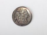 une pièce d'argent sur laquelle figure l'image d'un groupe de personnes