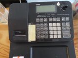 une calculatrice posée sur un bureau, avec un ordinateur portable à l'arrière-plan
