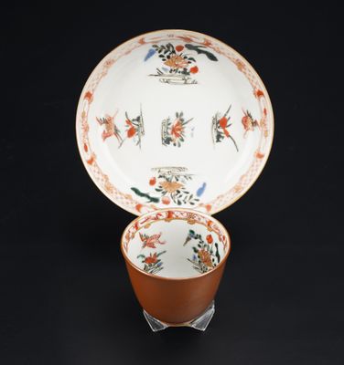 une tasse et une soucoupe orange et blanche posées sur une table noire