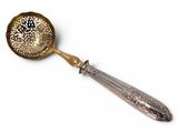 a silver spoon with a gold handle on a white surface