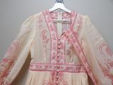 a pink and white dress on a hanger on a wall