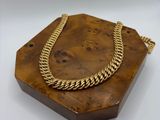 a gold necklace on a wooden stand with a chain