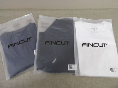 trois t-shirts portant l'inscription « fincut » sont posés sur un canapé