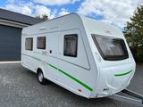 the small white camper is parked in front of a garage