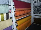 many different colored fabrics on a shelf in a room
