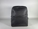 grey backpack sitting on a white surface with a white background