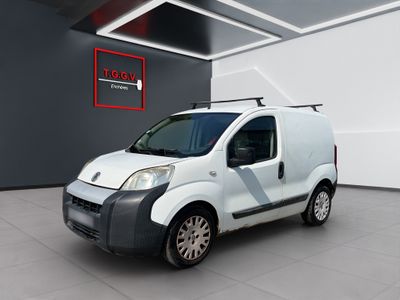 La petite camionnette blanche est garée dans une grande pièce.