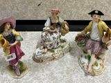 three figurines of people are sitting on a table