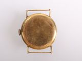 an overhead view of a gold plated pocket watch on a white surface