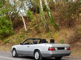 a silver convertible car driving down the road with its roof down