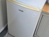 a small white refrigerator in the corner of a room