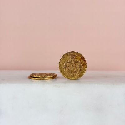 a gold coin sitting on top of a white table next to a pink wall