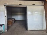 une grande porte ouverte dans un bâtiment où se trouvent des palettes de bois