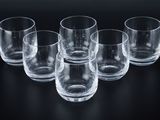 six empty glasses are lined up on a black surface