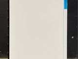 a white refrigerator sitting in a room with a black wall behind it