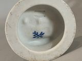 a small white vase with a blue flower on it