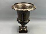 an antique silver vase sitting on top of a wooden base