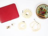 une boîte rouge contenant des perles et d'autres bijoux, posée sur un fond blanc