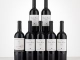 six bottles of red wine are lined up on a table