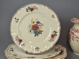 three plates and a vase sitting on a table